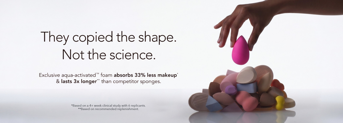 A hand holds an Original Pink Beautyblender makeup sponge above a pile of dupe makeup sponges on a clean white background. Promotional text says: They copied the shape not the science - Exclusive aqua-activated foam absorbs 33% less makeup & lasts 3x longer than competitor sponges (Based on a 4+ week clinical study with 6 replicants; and recommended replenishment).